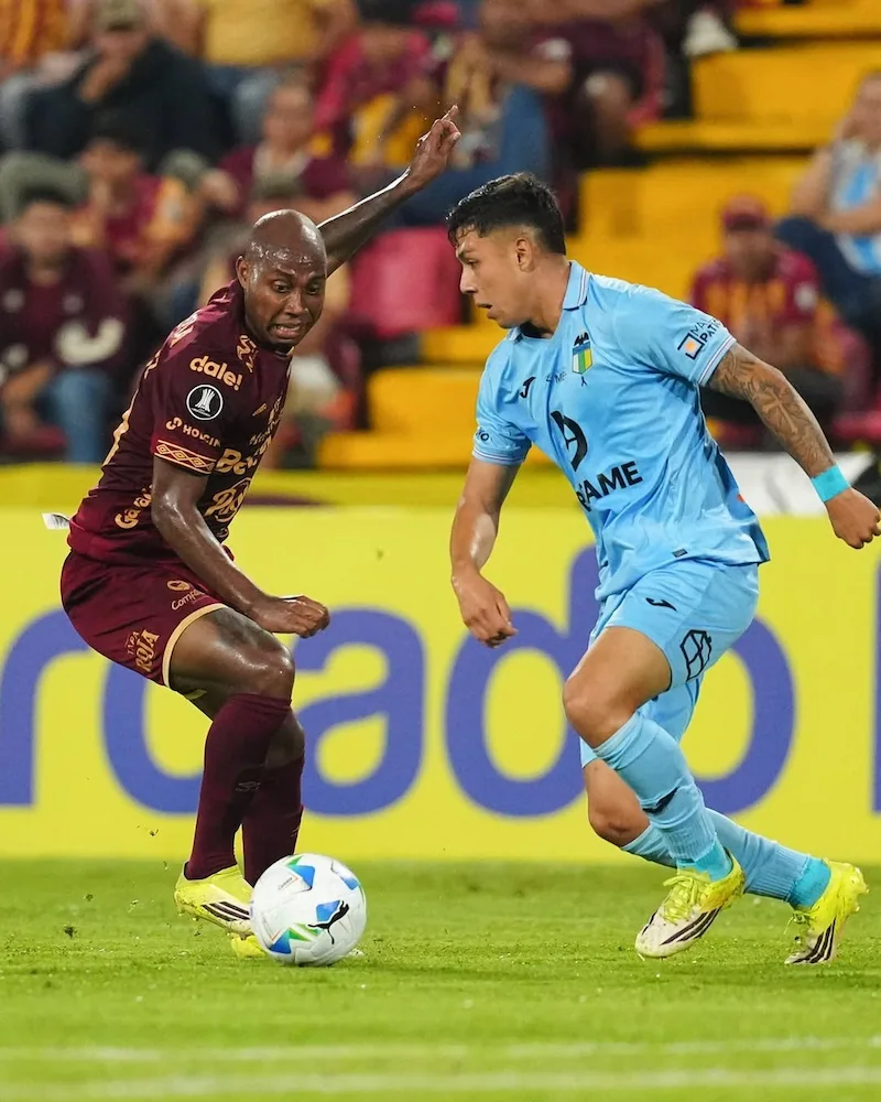 Potes do sorteio da fase de grupos Libertadores 2026 Definidos os classificados após 1103 - Foto de dois jogadores de futebol, um do Deportes Tolima (colômbia) e outro do O'Higgins (Chile), disputando a bola com intensidade durante uma partida da Copa Libertadores. O jogo acontece à noite em um estádio lotado.
